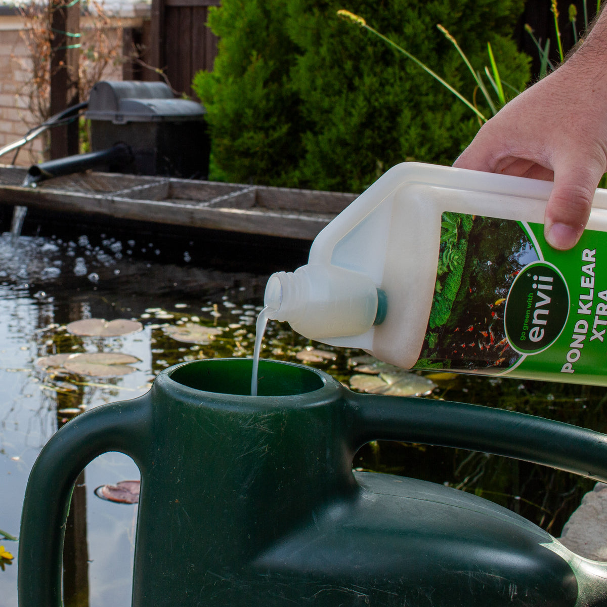 Pouring Pond Klear Xtra into a watering can.